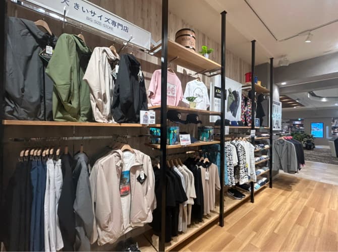 大きいサイズ専門店の売り場で、ジャケットやパーカーが棚に整然と並ぶ様子